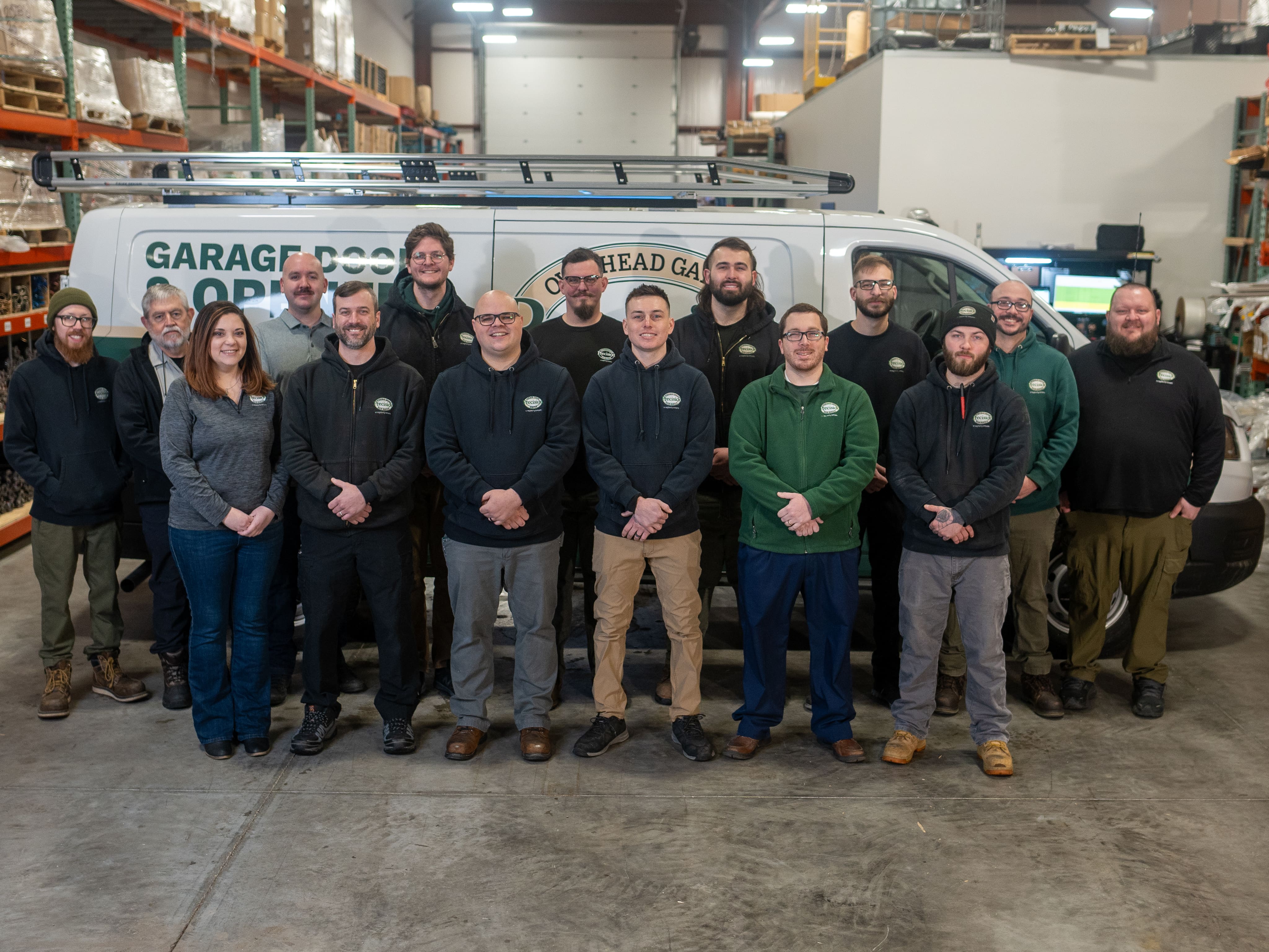 Precision Door Fort Wayne Team Standing In Front of Company Van in their Warehouse.